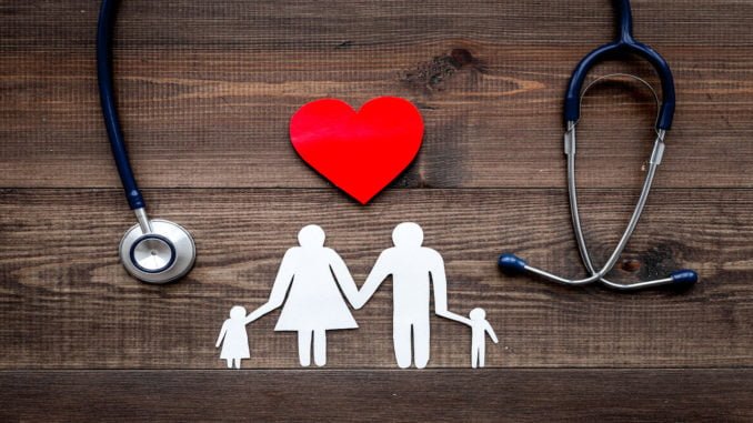 Take out health insurance for family. Stethoscope, paper heart and silhouette of family on wooden background top view